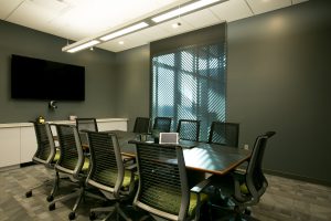 Corporate meeting and video conference room with four chairs and one LCD display panel on the wall with video camera and microphone