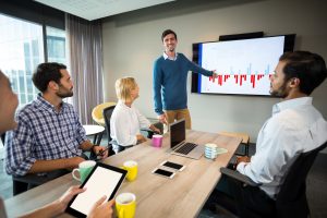 Meeting room with multiple people and display with results data