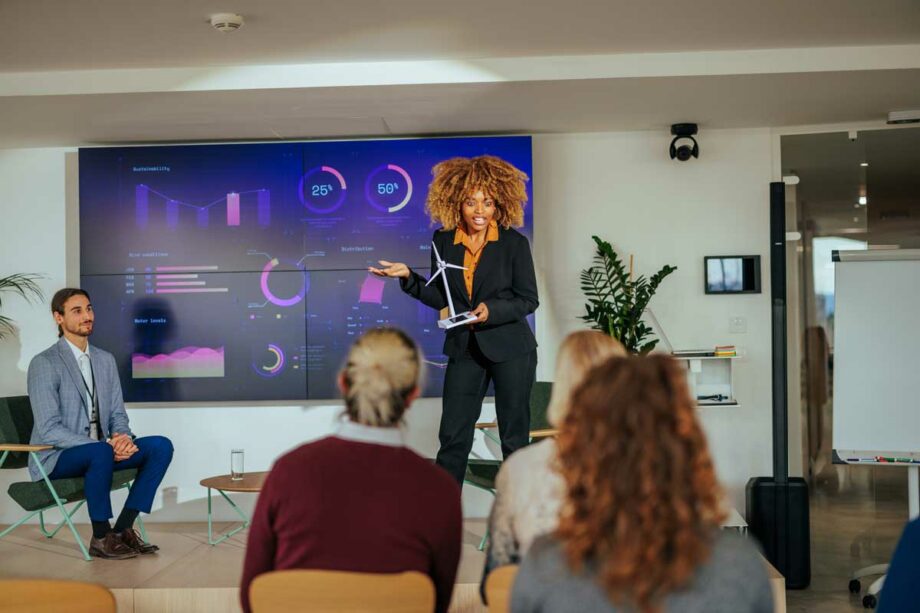 Woman with red hair giving a presentation on an LED